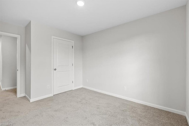 unfurnished bedroom with light colored carpet and a closet