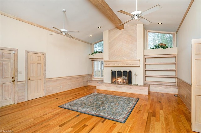 unfurnished living room with a large fireplace, ceiling fan, light hardwood / wood-style flooring, and high vaulted ceiling