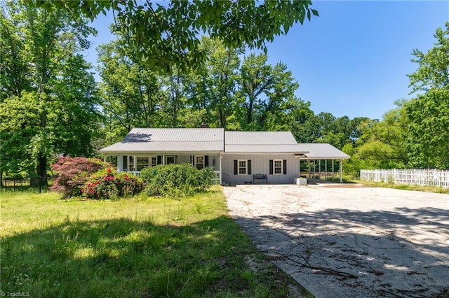 view of front facade featuring fence, concrete driveway, and metal roof