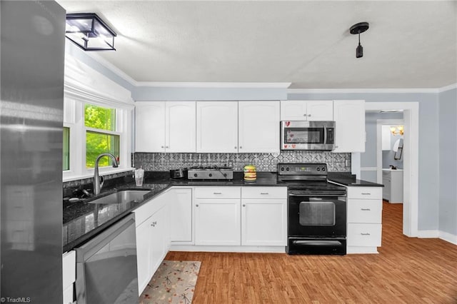 kitchen with appliances with stainless steel finishes, a sink, tasteful backsplash, light wood finished floors, and white cabinetry