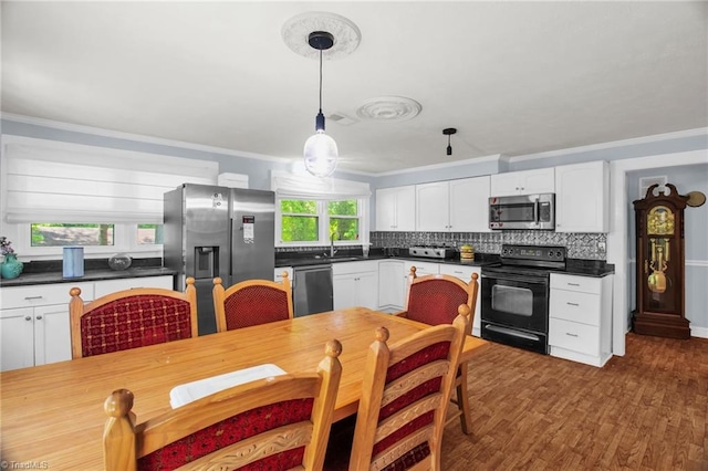 kitchen with stainless steel appliances, ornamental molding, white cabinets, dark countertops, and decorative backsplash