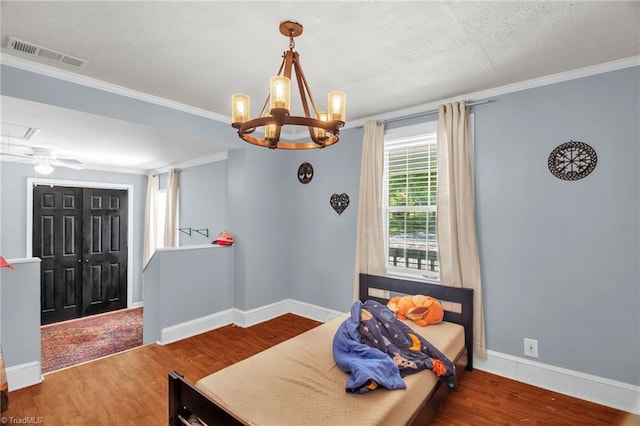 dining space featuring ornamental molding, wood finished floors, a textured ceiling, a chandelier, and baseboards