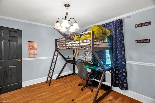 bedroom with ornamental molding, wood finished floors, baseboards, and a chandelier