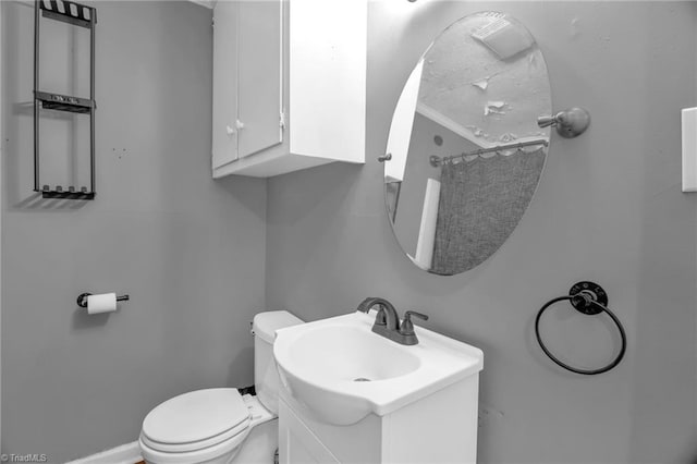 bathroom featuring toilet, baseboards, and vanity