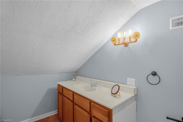 bathroom with lofted ceiling, a textured ceiling, a sink, and tile patterned floors