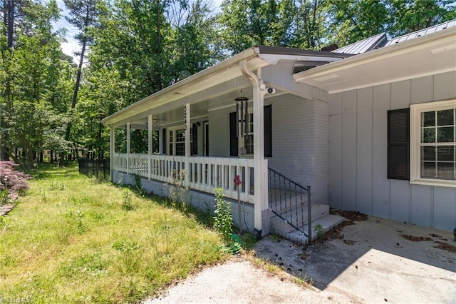 view of property exterior featuring a porch, brick siding, a standing seam roof, board and batten siding, and metal roof