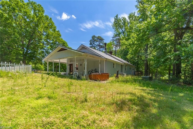 rear view of house featuring a hot tub, fence, an attached carport, and board and batten siding