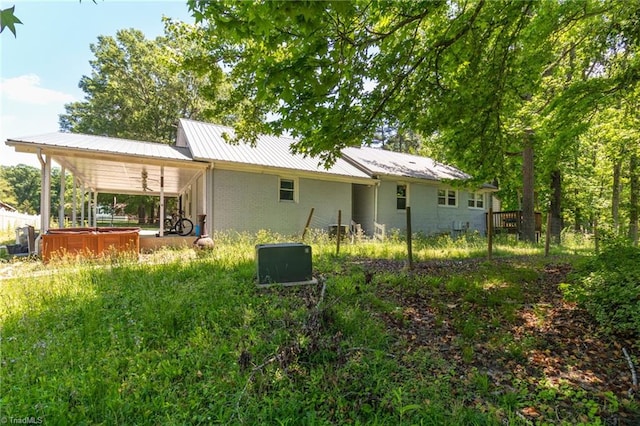 rear view of house featuring ceiling fan, metal roof, a hot tub, and brick siding