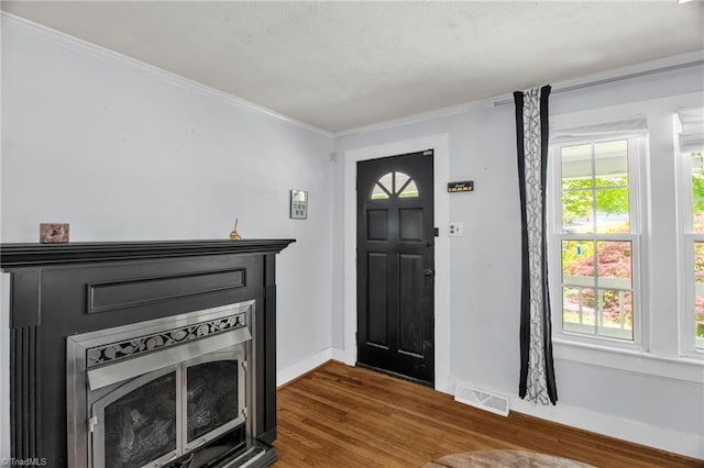 foyer featuring dark wood finished floors, a fireplace, baseboards, and crown molding