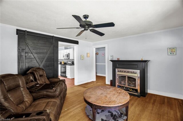 living area with wood finished floors, ceiling fan, baseboards, a fireplace, and crown molding