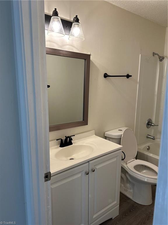 full bathroom with shower / bathtub combination, vanity, a textured ceiling, hardwood / wood-style flooring, and toilet