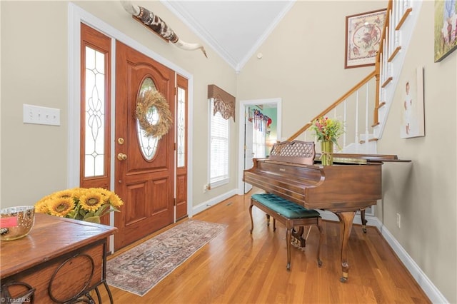 entryway featuring light wood-type flooring, vaulted ceiling, and ornamental molding