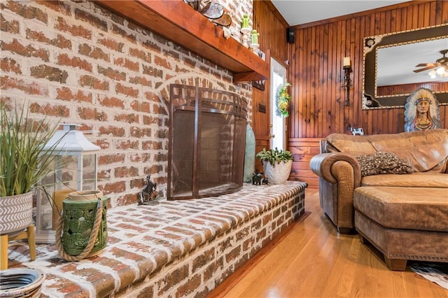 interior space featuring ceiling fan, wood walls, light wood-type flooring, and brick wall