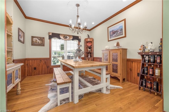 dining area featuring light hardwood / wood-style floors, ornamental molding, and an inviting chandelier