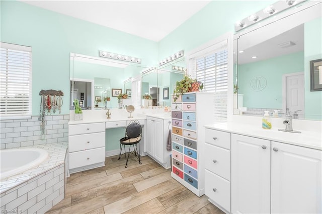 bathroom featuring a relaxing tiled tub and vanity