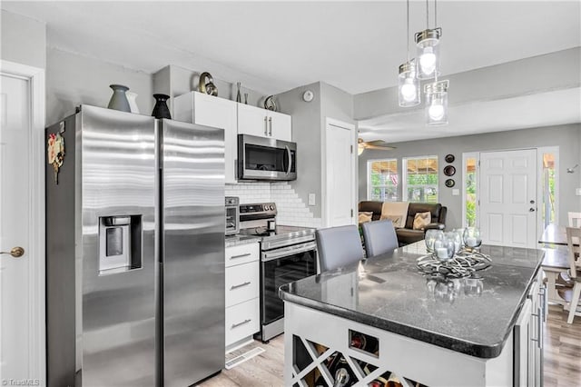 kitchen featuring ceiling fan, backsplash, appliances with stainless steel finishes, light wood-type flooring, and white cabinetry