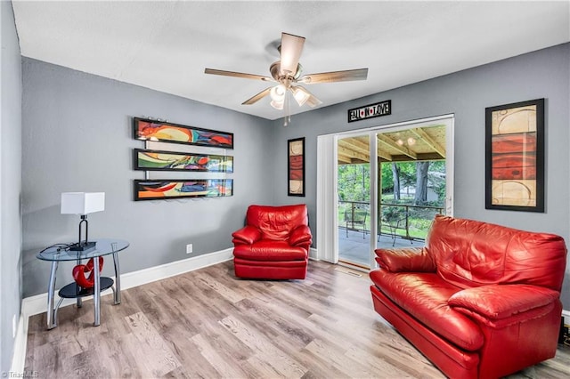 sitting room with baseboards, ceiling fan, and wood finished floors
