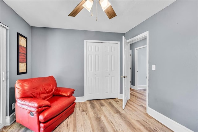 living area with baseboards, a ceiling fan, and wood finished floors