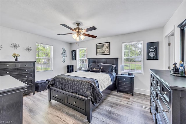bedroom with light wood-style floors, baseboards, and ceiling fan