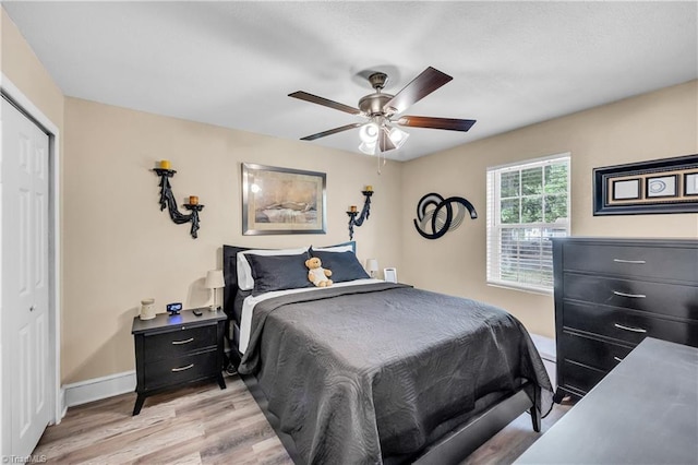 bedroom featuring baseboards, a ceiling fan, a closet, and light wood-type flooring