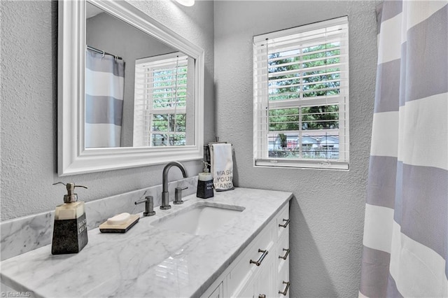 full bathroom featuring vanity, a textured wall, and a shower with curtain