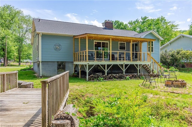 back of house with a wooden deck, a chimney, a yard, and an outdoor fire pit