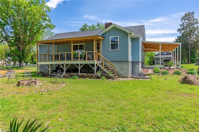 rear view of house with a lawn, a chimney, and a fire pit