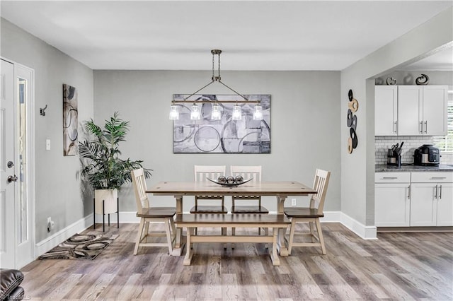 dining space featuring baseboards and light wood finished floors