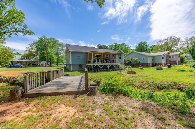 back of house with a chimney, a yard, an outdoor fire pit, and a deck