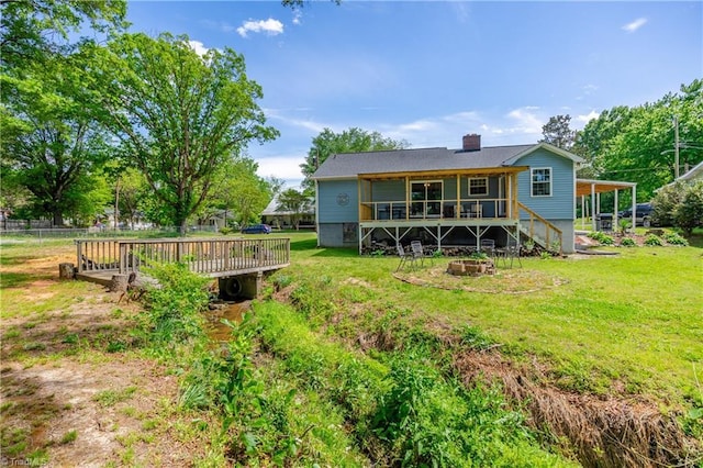 back of house featuring an outdoor fire pit, a deck, stairway, a chimney, and a yard