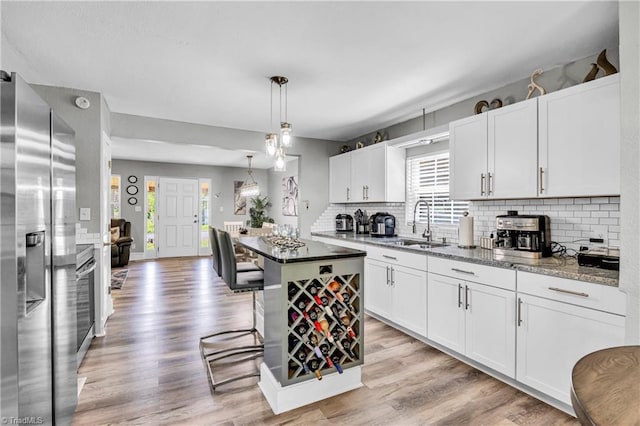 kitchen featuring a sink, stainless steel fridge with ice dispenser, backsplash, and a healthy amount of sunlight