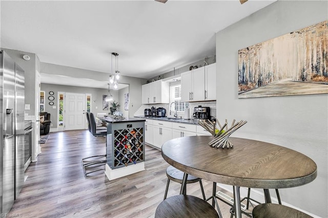 kitchen featuring a kitchen island, tasteful backsplash, a sink, light wood-style floors, and white cabinetry