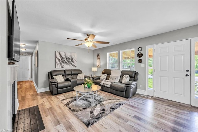 living area featuring a ceiling fan, baseboards, and wood finished floors