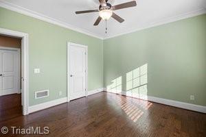 interior space with dark wood-type flooring, ornamental molding, and ceiling fan