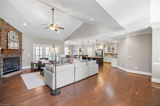 living room with a stone fireplace, high vaulted ceiling, dark hardwood / wood-style floors, and ceiling fan