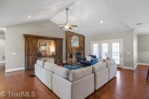 living room featuring lofted ceiling, a brick fireplace, dark hardwood / wood-style flooring, and ceiling fan