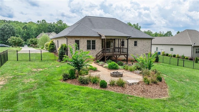 rear view of house with a yard, a sunroom, and an outdoor fire pit