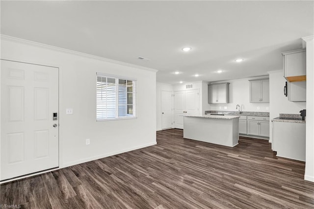 kitchen featuring baseboards, visible vents, dark wood-style floors, a center island, and crown molding