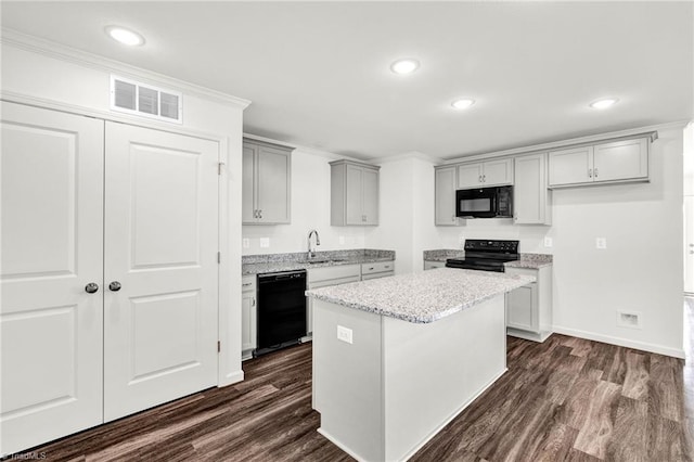 kitchen featuring gray cabinetry, dark wood-style flooring, a sink, visible vents, and black appliances