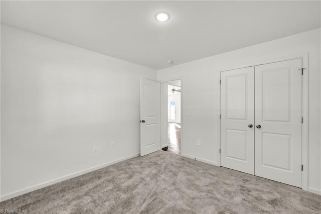 unfurnished bedroom featuring a closet, baseboards, and carpet flooring