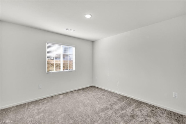 empty room featuring carpet floors, visible vents, and baseboards