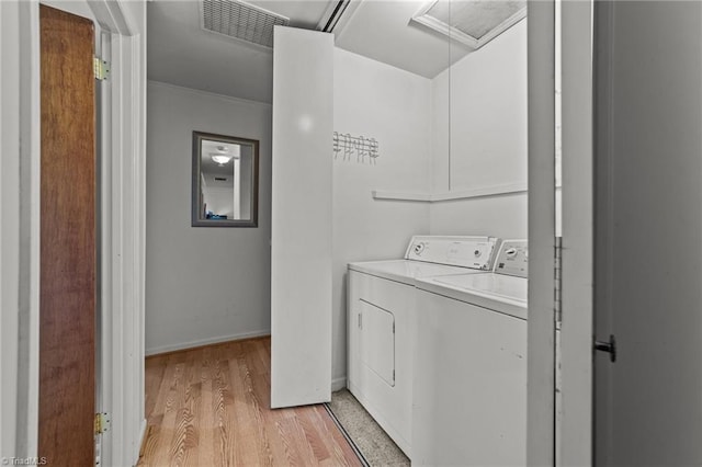 clothes washing area with washing machine and dryer and light hardwood / wood-style floors