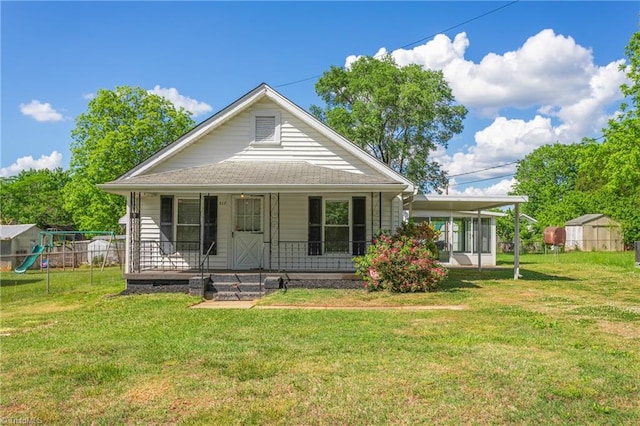 bungalow-style home featuring a front lawn, covered porch, and a storage unit