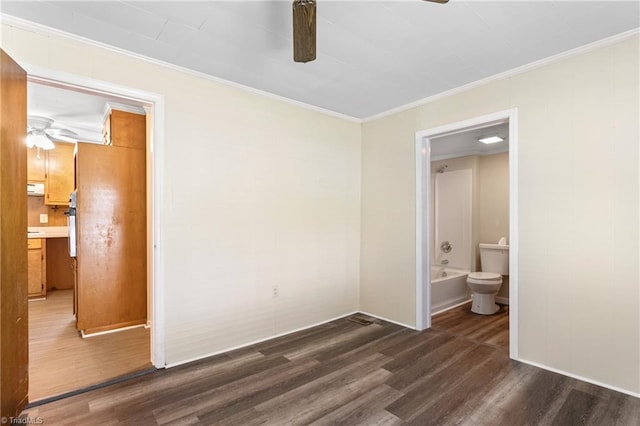 unfurnished bedroom featuring crown molding, dark wood-type flooring, ceiling fan, and ensuite bathroom