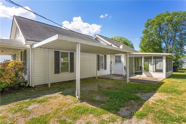 back of house featuring a sunroom and a lawn