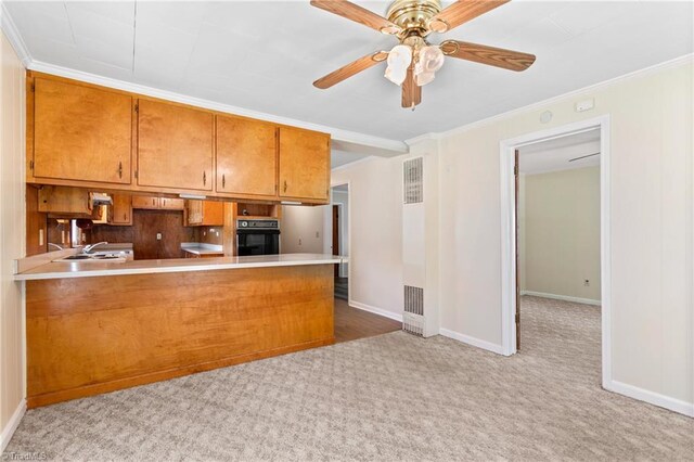 kitchen featuring ceiling fan, light carpet, oven, and kitchen peninsula