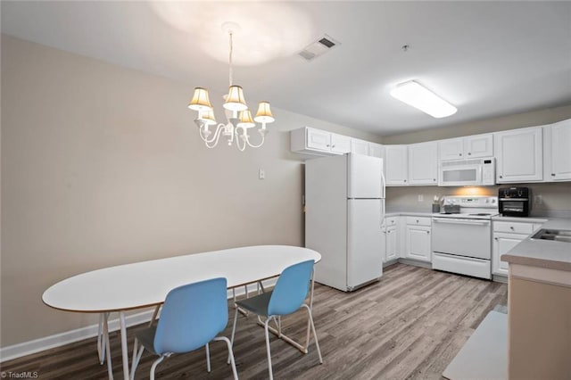 kitchen featuring an inviting chandelier, light wood finished floors, white appliances, light countertops, and visible vents