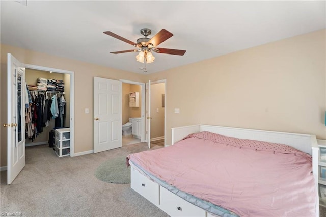 bedroom with ceiling fan, ensuite bath, carpet, a spacious closet, and a closet