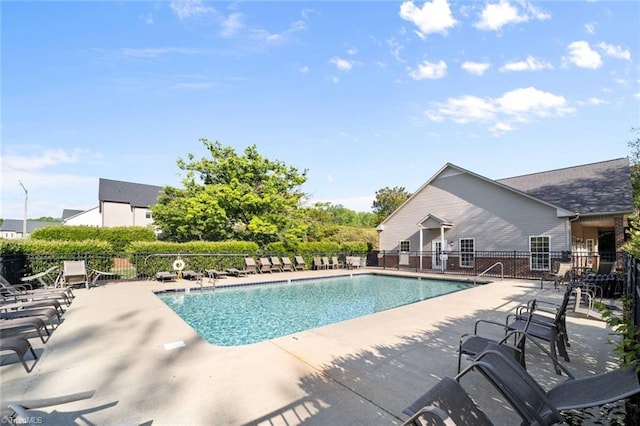 community pool with fence and a patio area