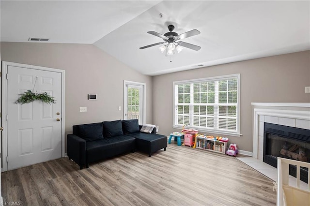 living area with visible vents, wood finished floors, a fireplace, a ceiling fan, and vaulted ceiling